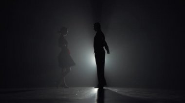 Genç kadın eşine yaklaşır ve çift Arjantin tangosu yapar. Stüdyodaki ışıklara karşı karanlık siluetler. Latin dansları okulunda koreografi dersi. Yavaş çekim hazır, 4K 59.94fps 'de..