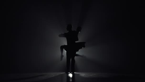 Elementi di tango argentino appassionato eseguiti da due ballerini. Silhouette di uomo e donna che ballano coreografie di danza latina al buio con retroilluminazione e fumo. Rallentatore pronto, 4K a 59.94fps. — Video Stock