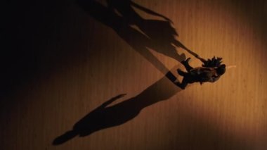 Birbirine yaklaşan iki dansçının üst görünümü ve tango yapmaya başlaması. Latince salon dansının elementleri stüdyoda kahverengi arka planda ve dans eden gölgelerde. Yavaş çekim hazır, 4K 59.94fps 'de..