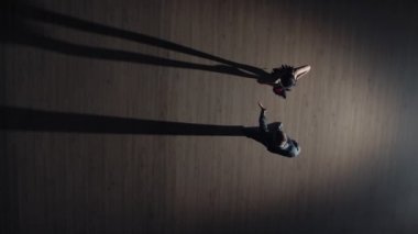 Birbirine yaklaşan iki dansçının üst görünümü ve tango yapmaya başlaması. Stüdyoda, gri arka planı ve dans eden gölgeleri olan Latin dansı öğeleri. Yavaş çekim hazır, 4K 59.94fps 'de..