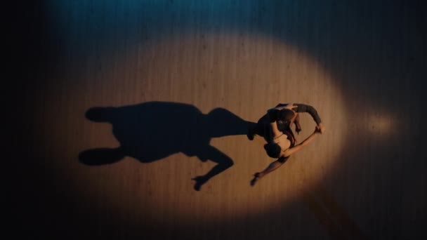 Vista superior de um par de dançarinos dançando elementos tango argentinos em um piso em parquet com sombras dançantes. Movimentos apaixonados de parceiros na dança latina. Movimento lento pronto, 4K a 59.94fps. — Vídeo de Stock