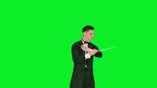 Руководитель оркестра в костюме дирижирует дубинкой, чтобы синхронизировать музыкантов. Маэстро режиссирует музыкантов движением палки на зеленом экране в студии. Концерт классической музыки. Закрыть. — стоковое видео