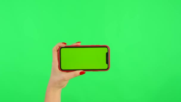 Женщина держит мобильный телефон с макетом рабочего пространства в руках на зеленом фоне в горизонтальном положении. Женская рука касается, кликает, постукивает, приближается, тянет и скользит. Закрыть — стоковое видео