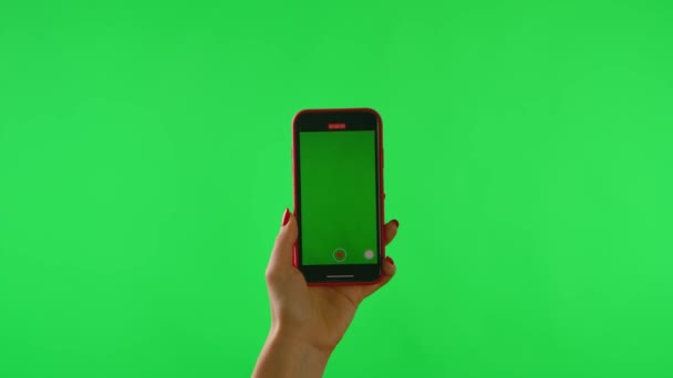 Mujer sostiene el teléfono móvil con el espacio de trabajo pantalla simulada sobre fondo verde. Hembra botón de hacer clic en la mano para tomar el vídeo, acercar para navegar. Paquete de gestos. Área de publicidad. Lugar de la plantilla. De cerca.. — Vídeos de Stock