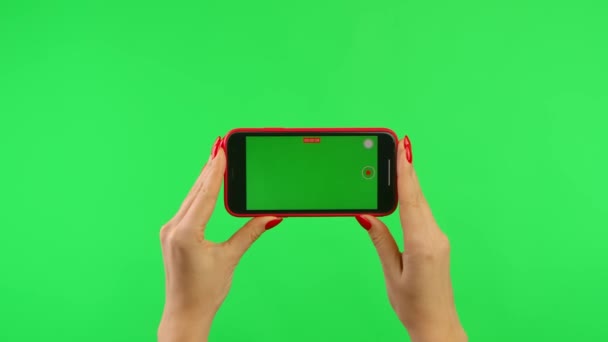 Vrouw houdt mobiele telefoon met werkruimte mock up scherm op groene achtergrond in horizontale positie. Vrouwelijke hand te klikken knop om video te nemen. Een gebaren roedel. Reclamegebied. Template plaats. Sluiten.. — Stockvideo