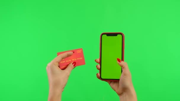 Kvinnlig hand håller mobiltelefon med arbetsyta modell upp skärmen på grön bakgrund. Kvinna gör ett online-köp med kreditkort och smartphone. Reklam område. Mall plats. Närbild. — Stockvideo