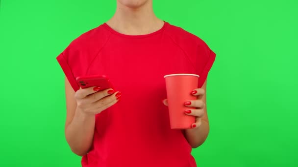 빨간 티셔츠를 입은 여성은 스마트폰에서 정보를 보고 작업 공간에서 핸드폰으로 녹색 배경 화면을 보는 장면을 보여준다. 광고 지역. 템플릿 장소. 닫아. — 비디오