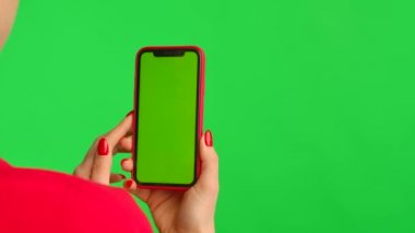 Kadının elinde çalışma alanı olan cep telefonu var. Yeşil arka planda ekran görüntüsü var. Kadın eli dokunuyor, tıkırdıyor, tıkırdıyor, kayıyor, kayıyor, yakınlaştırıyor. Reklam alanı. Şablon yeri. Kapat..
