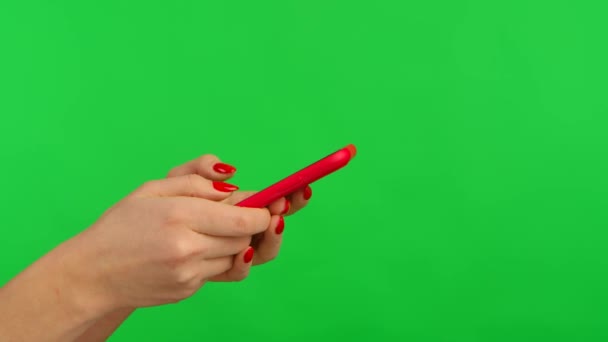 Side view of female hands texting on her smartphone on green screen chroma key background. Fingers touching touchscreen, zoom in, swiping, sliding and clicking. Woman browsing the Internet. Close up. — Stock Video