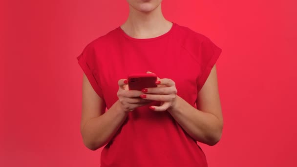 Vrouw sms 'en op smartphone en demonstreert telefoon met groene werkruimte mock up scherm op rode achtergrond. Vrouw die informatie laat zien. Reclamegebied. Template plaats. Sluiten.. — Stockvideo