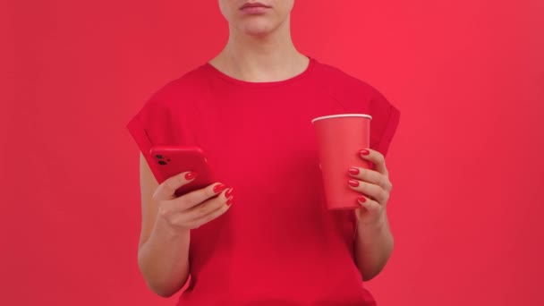 Mujer ve la información en el teléfono inteligente y demuestra el teléfono con el espacio de trabajo verde pantalla de la maqueta sobre fondo rojo. Área de publicidad. Plantilla de lugar para texto o imagen, contenido promocional. De cerca.. — Vídeo de stock