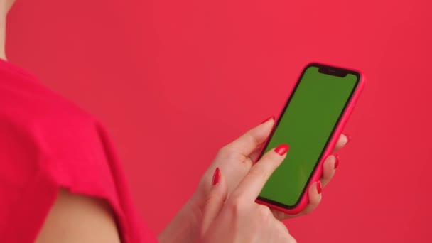 Nő tartja mobiltelefon zöld munkaterület mock up képernyő piros stúdió háttér. Női kéz megérintése, kattintás, érintés, csúszkálás, lopás. Hirdetési terület. Sablon hely. Közelről.. — Stock videók