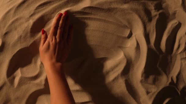 Vrouwelijke hand trekt hart op het zand. Close-up van vrouwen hand gladstrijkt het zanderige oppervlak en trekken hart vorm. Valentijnsdag symbool. Romantische vakanties aan zee, liefde, zomervakantie. Langzame beweging. — Stockvideo