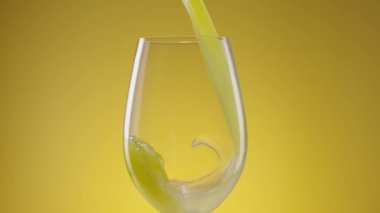 Bir bardağa taze sıkılmış doğal portakal suyu döküldü. Sarı arka planda limonata ya da limonata. Diyet sağlıklı tropikal kahvaltı içeceği. Ağır çekim. Kapat..