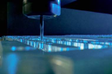 Metal işleten CNC değirmen makinesi. Delme çeliği. Bir sondaj makinesi metali işliyor, bir şekli kesiyor. Detayların modern işleme teknolojisi. Endüstriyel detayları mavi ışıkta kapatıyoruz.