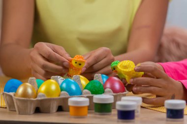 Anne ve kızı dekoratif piliçlerle eğleniyor. Afro-Amerikalı kadın ve küçük kız evdeki dekore edilmiş odada masada oturuyorlar. Mutlu Paskalyalar. Kapat..