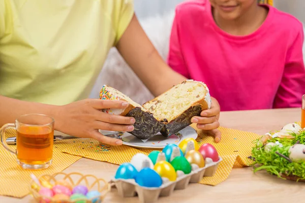 Mamma taglia una torta di Pasqua per curare sua figlia. Donna afroamericana e bambina sono seduti a tavola in una stanza decorata a festa a casa. Buona Pasqua. Da vicino.. — Foto Stock