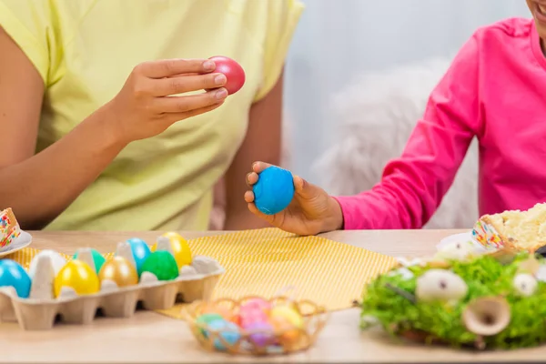 Mamma e figlia si divertono e rompono le uova di Pasqua. Donna afroamericana e bambina sono seduti a tavola in una stanza decorata a festa a casa. Buona Pasqua. Da vicino.. — Foto Stock