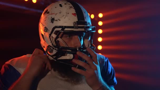 Americký fotbal mistrovství hra: zblízka portrét profesionálního hráče, uvedení na helmu. Film zpomalení záběr na tmavém pozadí s červeným modrým světlem.