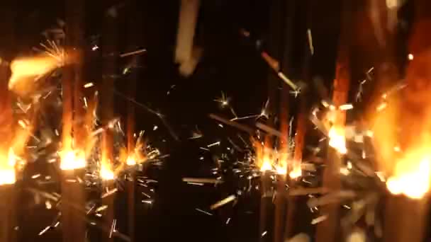 Csillogók fekete stúdió háttérrel. Csillogó bengáli tűzijáték arany szikrákkal a sötétben. Bengáli tüzek villognak. Fogantatás ünnep, újév, party, születésnap. Közelről. Lassú mozgás.. — Stock videók