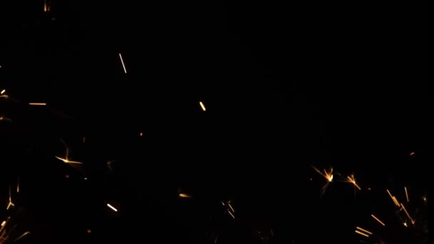Bengáli tüzek szikrázó fröccsenése fekete háttérrel. Világító csillagszóró a sötétben. Csillogó bengáli tűzijáték arany szikrákkal. Ünnep, újév, születésnap. Közelről. Lassú mozgás.. — Stock videók