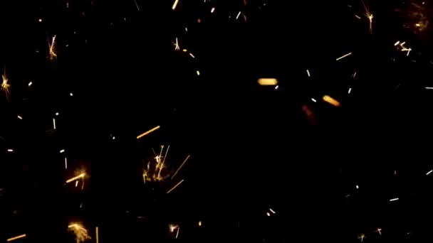 Sparkling splashes of bengal fires on black background. Lightening shine particles sparkler in dark. Sparkling bengali firework with golden splashes of sparks. Concept holiday. Close up. Slow motion. — Stock Video