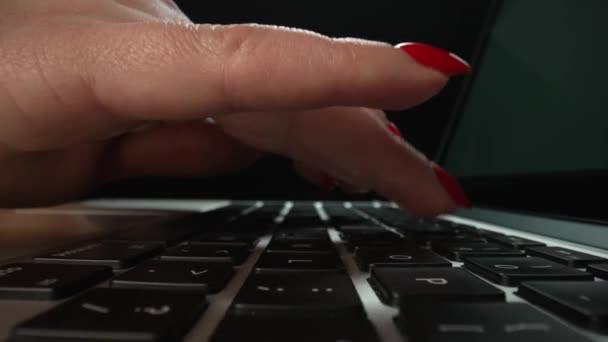 Macro dolly filmó imágenes deslizantes de manos femeninas escribiendo en el teclado del portátil en la oficina oscura. Los dedos femeninos tocan el teclado portátil. Trabajo independiente, educación en línea. De cerca. Movimiento lento. — Vídeos de Stock