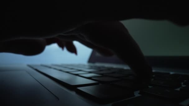 Woman working with laptop on desktop in dark. Woman freelancer typing on notebook at home office using keypad. Extreme close up of silhouette of female fingers on keyboard. Slow motion. — Stock Video