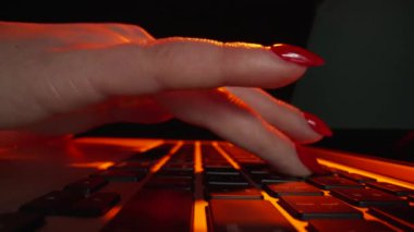 Düşük açılı çekimde, kadın elleri, klavyede kırmızı ışıkta dizüstü bilgisayarda yazarken görülüyor. Defter üzerinde çalışan bir kadın. Serbest çalışma, çevrimiçi eğitim, sosyal ağlar, iş. Kapatın. Yavaş çekim.