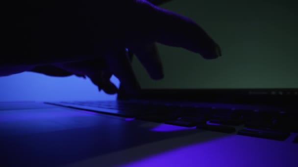 Disparo de ángulo bajo de manos femeninas escribiendo en el teclado del ordenador portátil en la oficina oscura con luz azul. Mujer trabajando en un cuaderno. Freelance, educación online, redes sociales, negocios. De cerca. Movimiento lento. — Vídeos de Stock