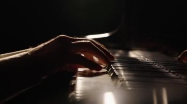 Erkek eller piyano tuşlarına dokunur ve hızlı caz melodisi çalar. Piyanist akorlar çalar karanlıkta piyanoda müzik yaratır. Müzik aletinin anahtarları. Müzisyenlerin parmakları birbirine yakın. Yavaş çekim 59.94fps 'te hazır..