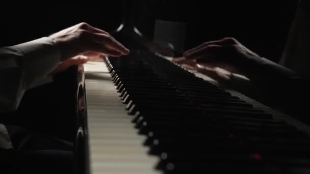 Les mains masculines jouent rapidement de la musique joyeuse au piano sur fond noir. Musicien touche touches blanches et noires de l'instrument avec ses doigts créant mélodie musicale. Ferme là. Mouvement lent prêt à 59.94fps — Video