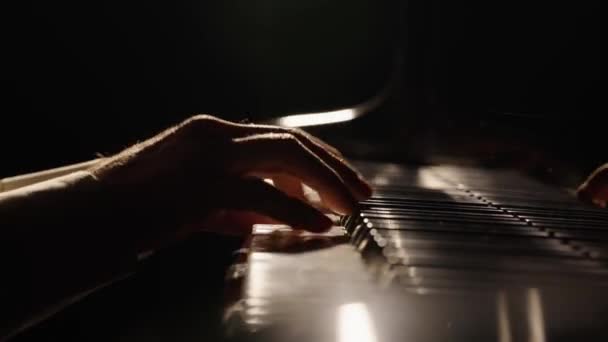 Чоловічі руки торкаються клавіш піаніно і грають швидку джазову мелодію. Піаніст грає акорди, створюючи музику на піаніно в темряві. Ключі від музичного інструменту. Музиканти пальці крупним планом. Повільний рух готовий до 59.94fps . — стокове відео