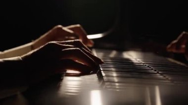 Erkek eller piyano tuşlarına dokunur ve hızlı caz melodisi çalar. Piyanist akorlar çalar karanlıkta piyanoda müzik yaratır. Müzik aletinin anahtarları. Müzisyenlerin parmakları birbirine yakın. Yavaş çekim 59.94fps 'te hazır..