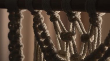 Dekorasyon ya da dekorasyon için bir çubuğa beyaz makrome iplikler deseni. Ev dekorasyonu fikri el yapımı makrome pamuk. Düğümlü dantel, iç dekorasyon için dekoratif süs. Kapat..