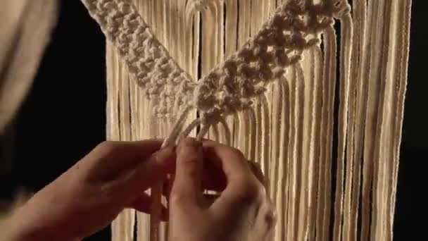 Жінка-майстер плете макраме з легких бавовняних ниток у своїй домашній майстерні. Жіночі руки зав'язують вузли, створюючи мереживо з ниток. Концепція ручної роботи. Творчий процес ремесел. крупним планом . — стокове відео