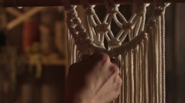 Kadınların elleri boho tarzında makrome örer. Kadın dantel yapmak için pamuk ipliklere düğüm atıyor. Yaratıcı atölye. Modern örgü doğal dekorasyon konsepti. İp ustası. Kapatın. Yavaş çekim.