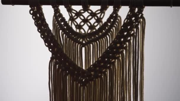 Woman craftsman weaves macrame from light cotton threads. Womens hands knit a beautiful lace ornament from knots on a white background in a darkened home workshop. Close up. Slow motion. — Stock Video
