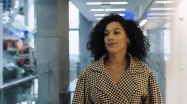 Mutlu Afro-Amerikan kadın alışveriş merkezinin önünden markalı kıyafetlerle geçiyor. Tarz sahibi bir kadın yeni sezonluk koleksiyona bakarken gülümser. Alışveriş konsepti. Yaklaştın. Yavaş çekim.