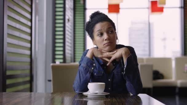 Утомлена молода афроамериканка сидить у кафе в торговому центрі після стомленого покуповування. Портрет засмученої жінки, що сидить над чашкою кави. Закрийся. Повільний рух. — стокове відео