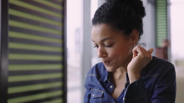 Jeune femme afro-américaine heureuse appréciant le café aromatique et le chocolat assis à des tables dans le café du centre commercial. Une femme se repose après un achat réussi dans un magasin de vêtements de mode. Presque. Mouvement lent. — Video