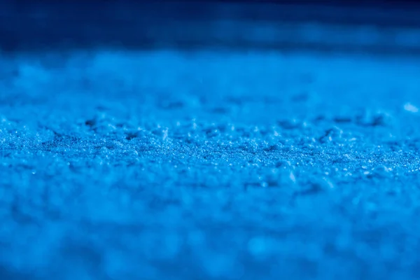 Tło lodu i tekstura z zadrapaniami od łyżwiarstwa i hokeja. Podłoga lodowiska, detal teksturowanego tła lodowego ze śniegiem i kryształami w niebieskim świetle. Puste lodowisko z bliska. — Zdjęcie stockowe