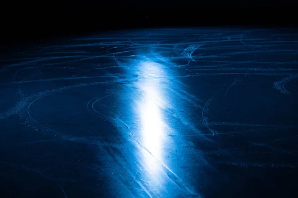 Lage hoek op ijsvlak in de arena voor kunstschaatsen of hockey. IJs achtergrond en ijs textuur is gesneden met patroon en krassen van schaatsen. Detail van gestructureerd ijs met sneeuw in blauw licht. Sluiten.. — Stockfoto