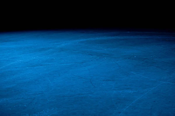 Baixo ângulo na superfície do gelo na arena para patinação artística ou hóquei. Fundo de gelo e textura de gelo é cortado com padrão e arranhões de patins. Detalhe de gelo texturizado com neve em luz azul. Fechar. — Fotografia de Stock