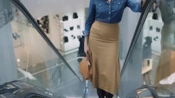 DNYPRO, UCRANIA - 1 DE DICIEMBRE DE 2021: Elegante mujer afroamericana sube escaleras mecánicas en el centro comercial. Compras y concepto de moda. Gran tienda moderna con ropa y bienes de marca. — Vídeos de Stock