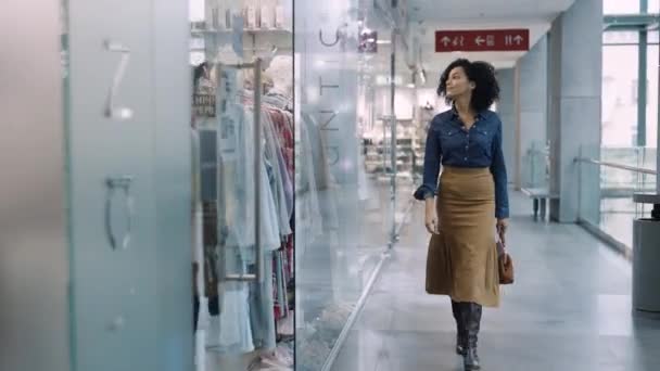 DNYPRO, UKRAINE - DECEMBER 1, 2021: Glad afroamerikansk kvinna går runt köpcentret och tittar på skyltfönstren med märkeskläder. Shopping och mode koncept. Stor modern butik. — Stockvideo
