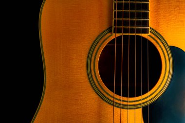 Sarı ahşap akustik gitar gövdesi ses deliği ve siyah stüdyo arka planında telleri var. Yaylı telli müzik aleti, rezonatörü kapat. Klasik klasik klasik gitar. Müzik ve sanat.