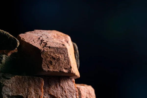 Pile of solid rough granite stone against a black studio background. Brown and gray granite. Stones for construction. Geology, ore, resources. Background from natural stones close up. — Stock Photo, Image