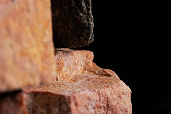 Högen av massiv grov granit sten mot en svart studio bakgrund. Brun och grå granit. Stenar för konstruktion. Geologi, malm, resurser. Bakgrund från naturliga stenar närbild. — Stockfoto