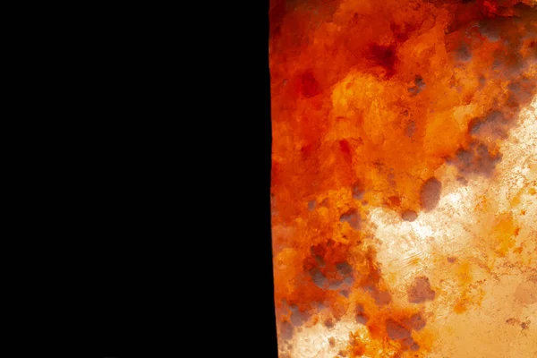 Pedaço de cristal laranja vermelho de sal marinho do Himalaia. Sal rosa cristal enorme natural sobre fundo preto isolado com luz de fundo. Cristal mineral para cozinhar, tempero, medicina, spa, saúde. Fechar — Fotografia de Stock